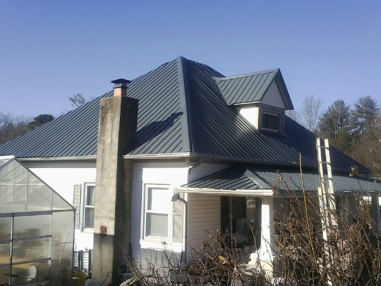Dark blue standing seam metal roof on a white farmhouse with dormer — Slate & Tile Roof Repair by Roofing Brothers in Tolono