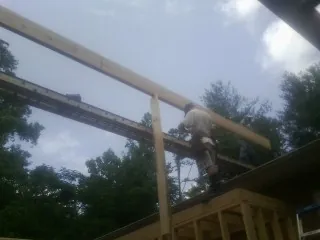 Carpenter setting a ridge beam over a new addition frame — Ice Dam Removal by Roofing Brothers in Tolono