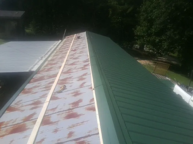 Old rusted panels beside newly installed green metal roofing — Wind Damage Roof Repair by Roofing Brothers in Tolono