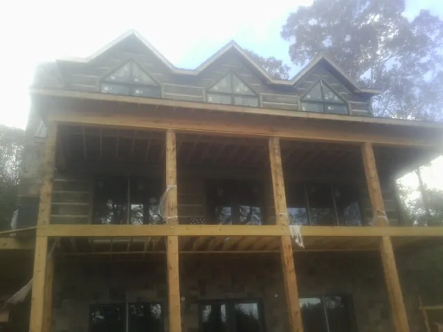 Dormers and porch framing on a large log home under construction — Roof Coating work by our crew in Tolono