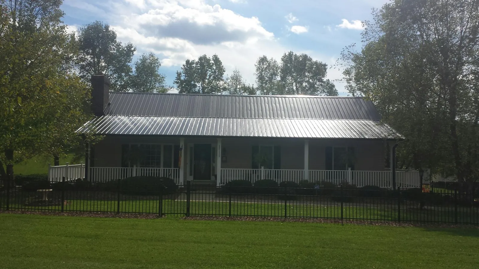 Gray metal roof on a brick ranch with a full width front porch — Gutter Guard Installation work by our crew in Tolono