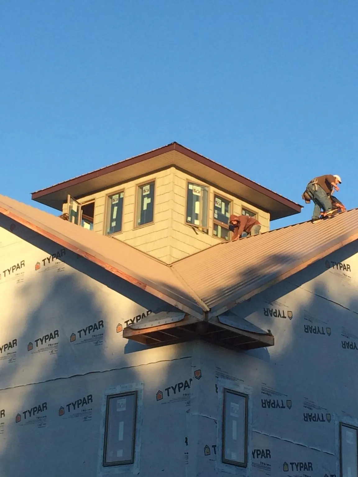 Roofers working around a rooftop cupola on a new metal roof at sunset — Roof Waterproofing in Tolono by Roofing Brothers